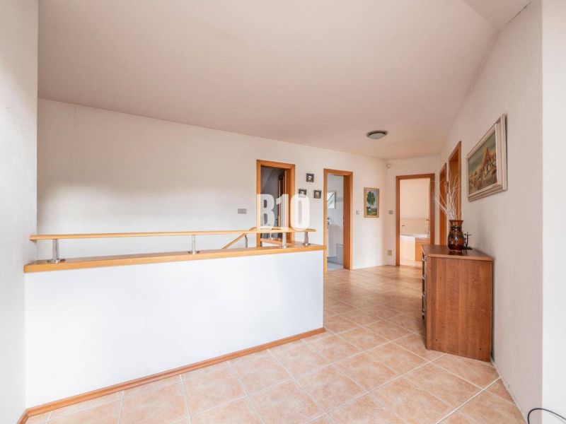 A hallway with ceramic tiles, wooden railing, and a wardrobe in a family house.