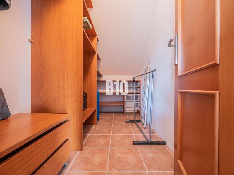 A wardrobe in a family house with cabinets, shelves, and a tiled floor.