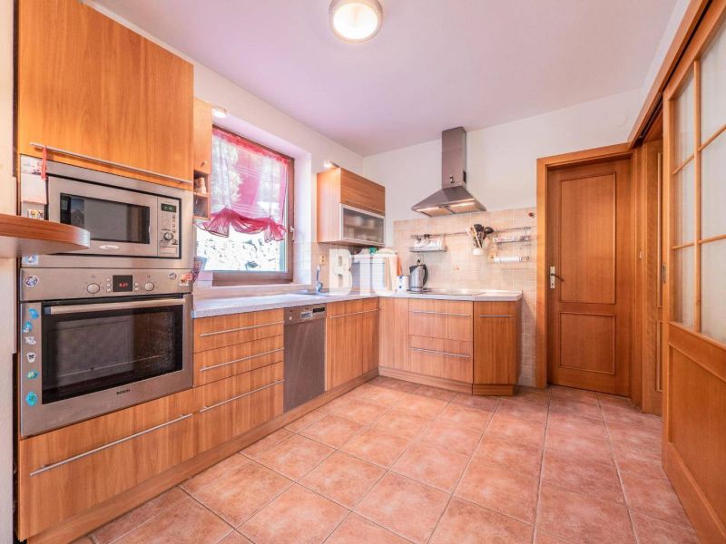 A kitchen in a family house with a tiled floor, wooden decor, and stainless steel appliances.