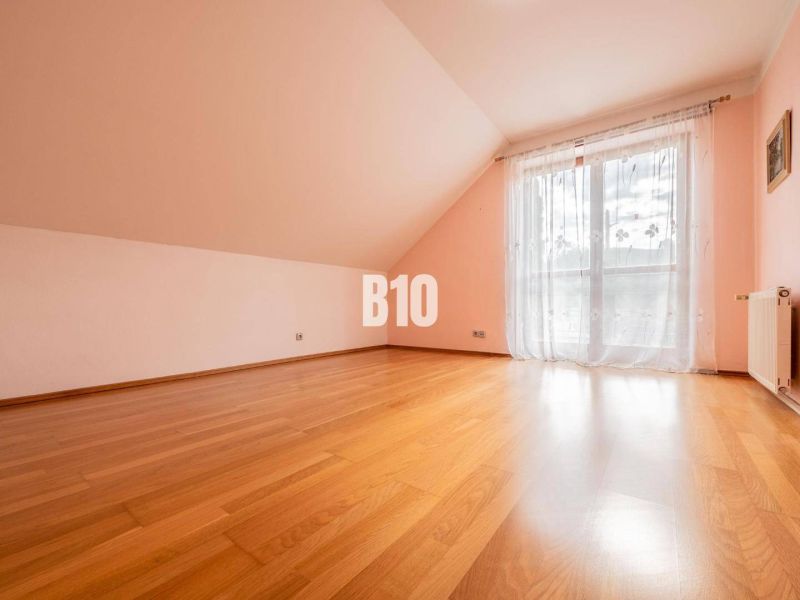A spacious room with a wooden floor and a French window in a family house.