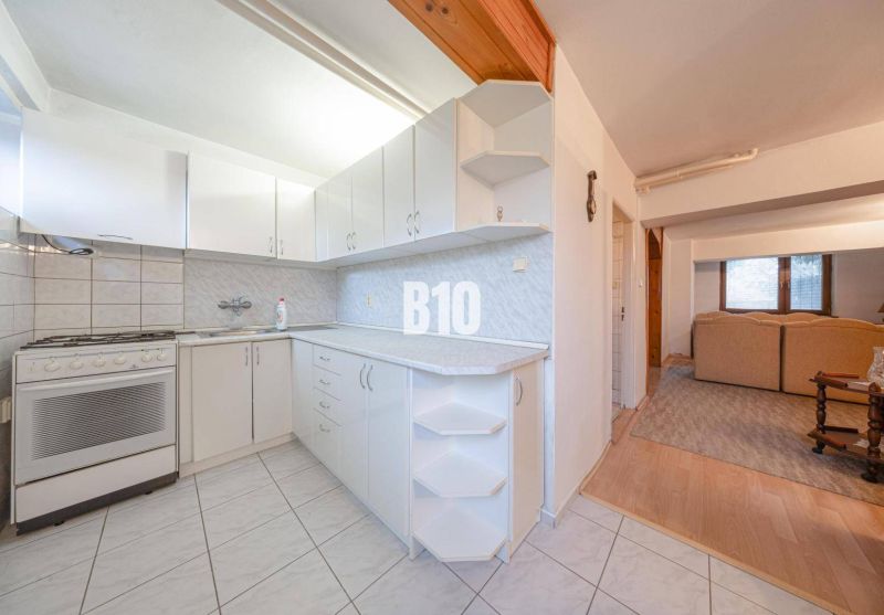 A kitchen in a family house with white kitchen cabinets and a tiled floor.