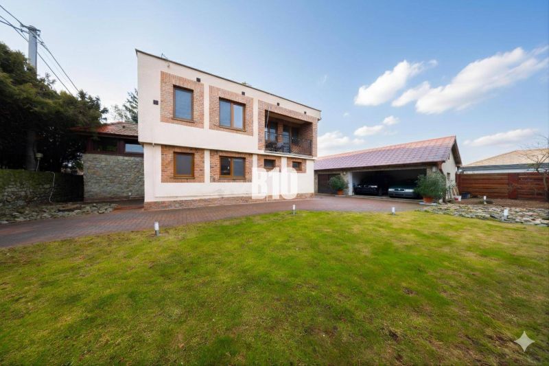 A family house in Štvrtok na Ostrove with a garage, grassy plot, and brick facade decor.