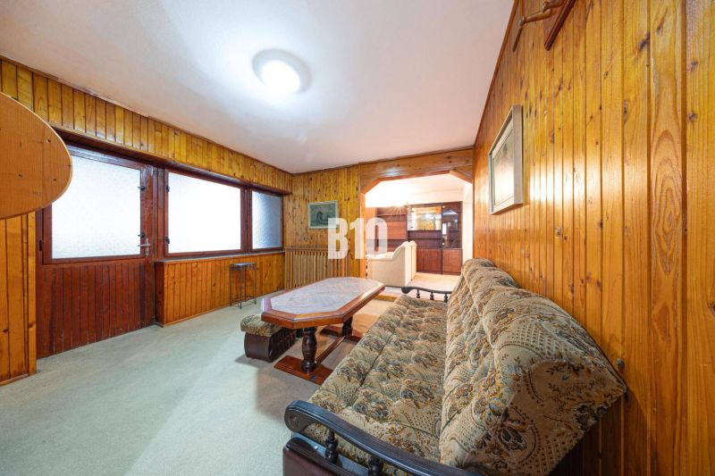 Living room of a family house with wooden paneling and a comfortable couch.