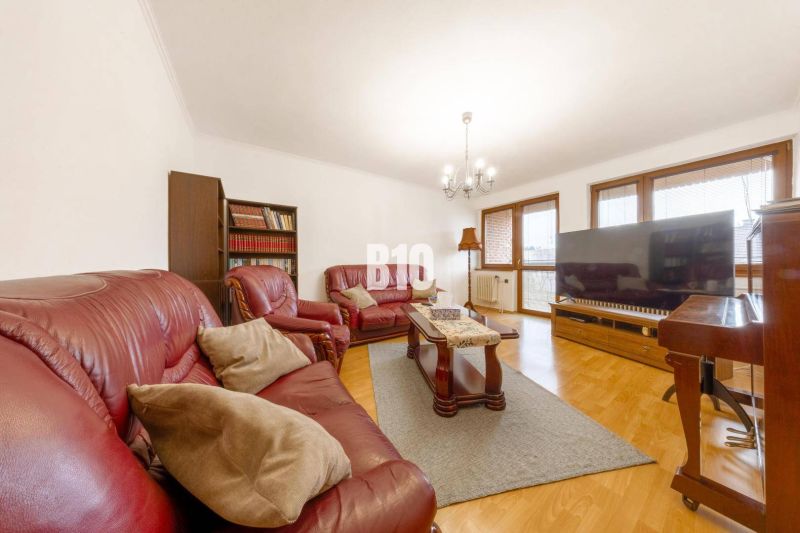 Living room in a family house with a leather sofa, bookshelf, and wooden decor flooring.