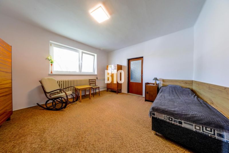 The interior of a family house with simple furniture, an armchair and a sofa, carpeted floor.