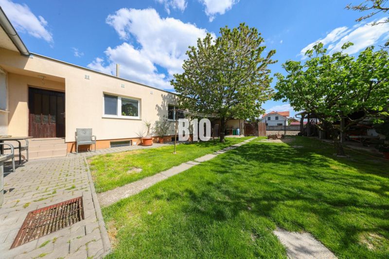 The exterior of a family house in Kalinkovo with a lawn, trees, and a terrace.