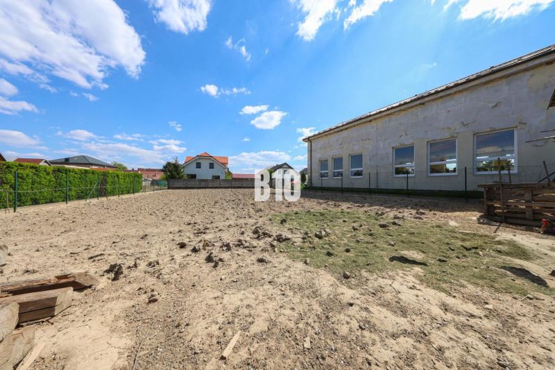 A plot of land with a view of a family house in Kalinkovo, bordered by fences, blue sky.