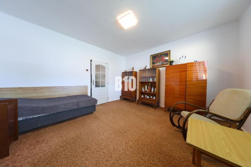 A room in a family house with a sofa, cabinets, and an armchair on a carpet.
