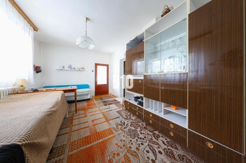 Interior of a family house with a sofa, cabinet, and dining table, carpet on the floor.