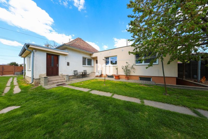 A family house in Kalinkovo with a well-maintained garden and two entrances under the blue sky.