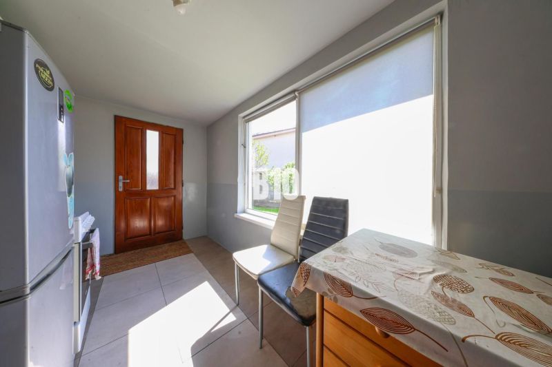 A kitchen in a family house with sunny windows and a wooden table.