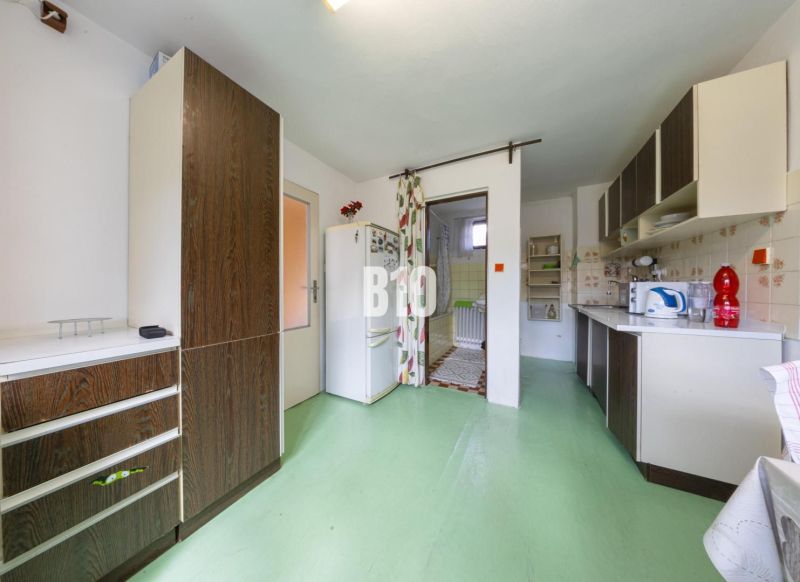 A kitchen in a family house with a green floor and wooden decor on the cabinets.