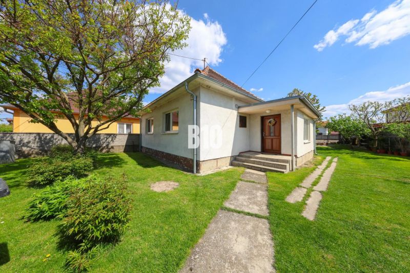 A family house in Kalinkovo with a front garden, a tree, and a path on the lawn.