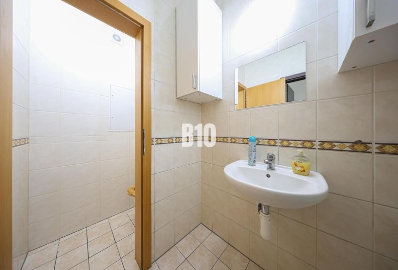 Bathroom with a sink and mirror, white tiles. Commercial spaces.