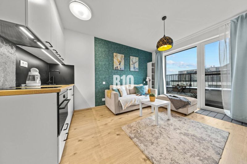 Living room with a kitchenette and a balcony in a studio apartment.