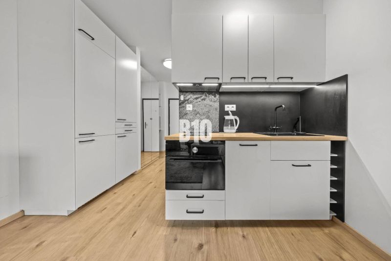 A kitchen with white cabinets, a black countertop, and a wood-patterned floor.