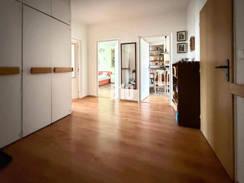 The hallway of a 3-room apartment with a wooden decor floor and built-in wardrobes.