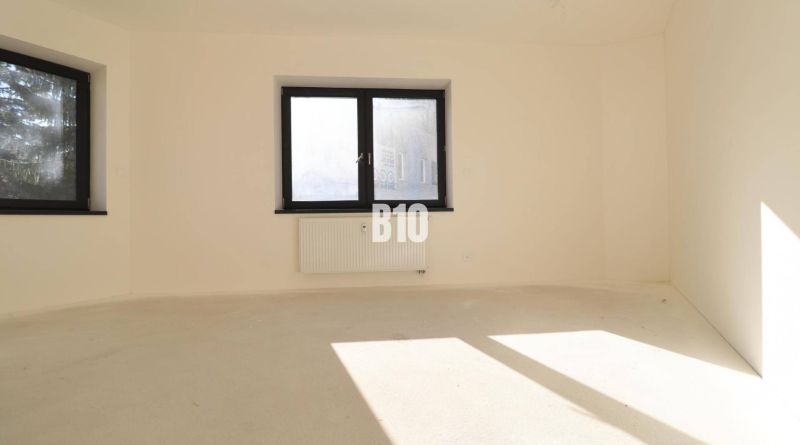 An empty office with two windows and a radiator, light walls, floor without wood decor.