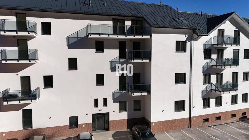 The facade of an apartment building in Dolný Kubín with a parking lot and balconies, ideal for a 2-room apartment.