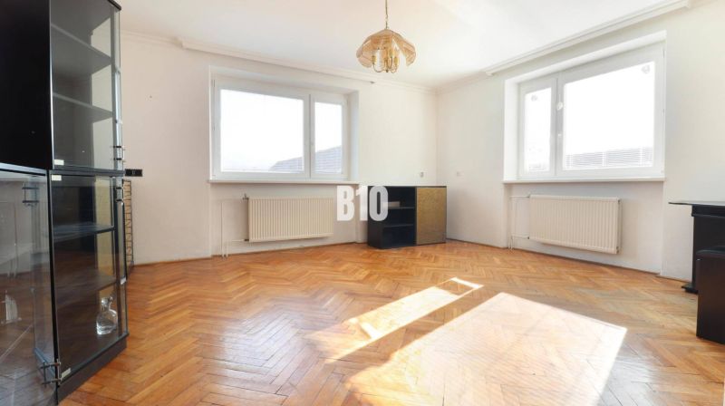 Living room with wood-patterned flooring and a glass display cabinet in a family house.