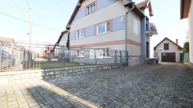 A family house in Turany with a stone fence and a paved courtyard.