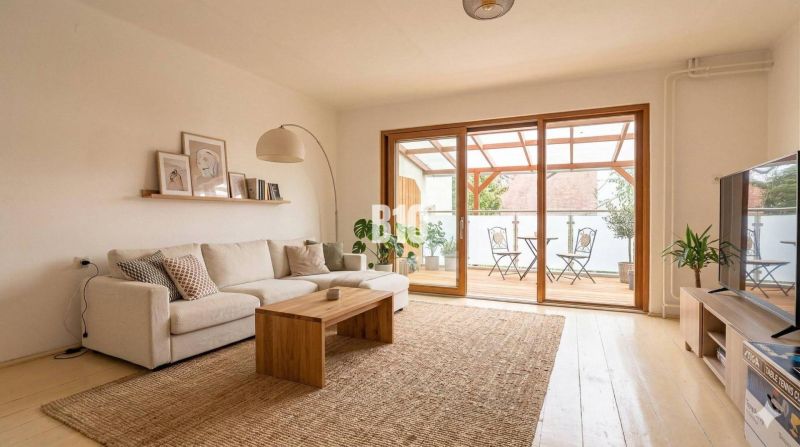 A living room in a family house with a light sofa, a wooden table, and a spacious terrace.