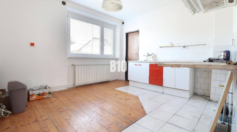 A kitchen in a family house with a wooden decor floor and white tiles.