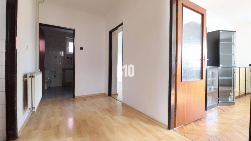 A hallway in a family house with a wooden decor floor and white walls.