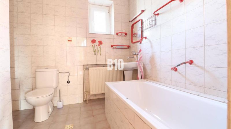 Bathroom in a family house with white tiles and red accessories.