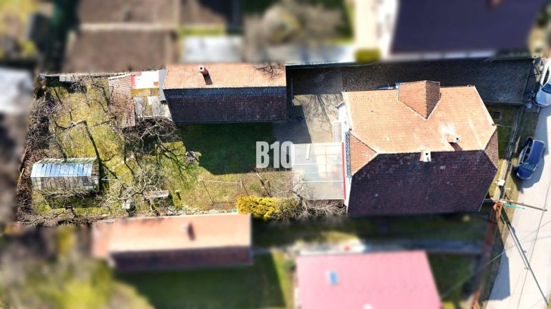 Aerial view of a family house in Turany with a yard and a greenhouse.