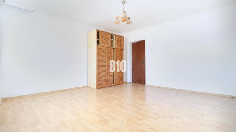 A spacious room with a wooden decor floor and a cabinet in a family house.