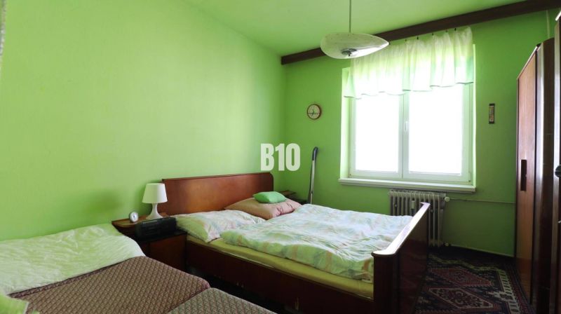 Green bedroom with two beds and furniture in a three-room apartment.
