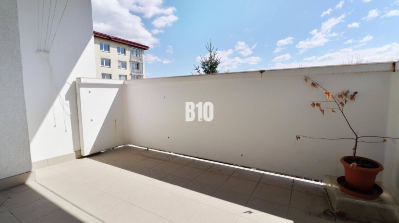 Balcony in a 3-room apartment. Plant in a pot, tiles, partial view of the neighboring building.