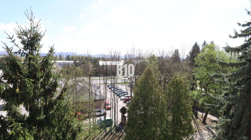 A view from a 3-room apartment in Martin, overlooking greenery and a parking lot.