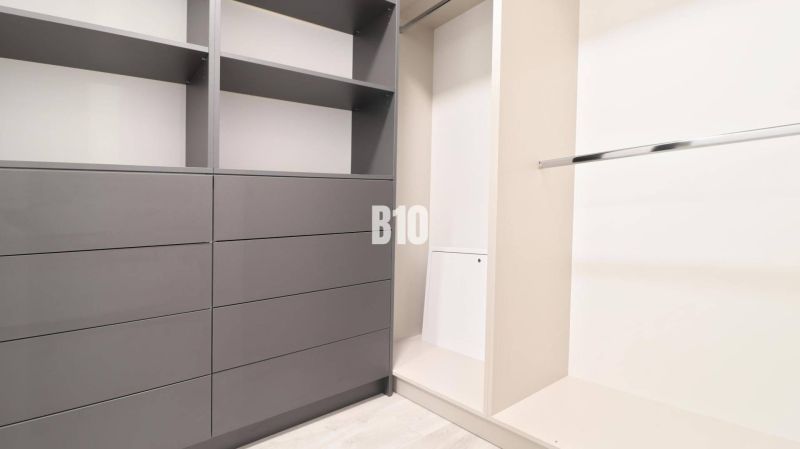 A wardrobe with gray cabinets and a hanging rod in a two-room apartment.