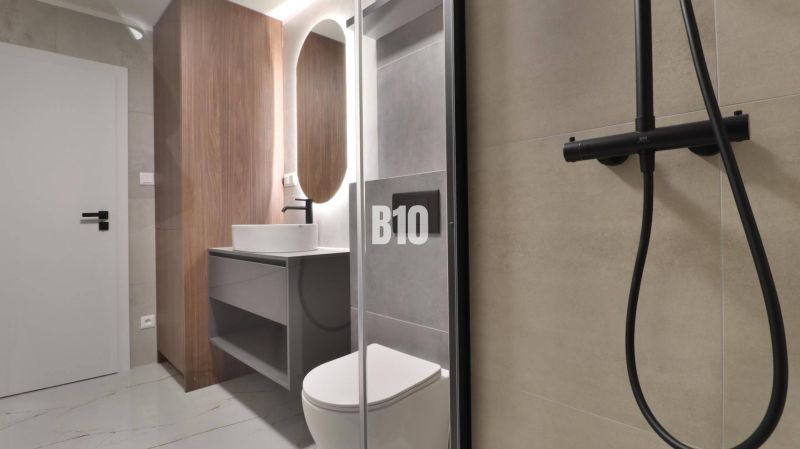 Bathroom in a 2-room apartment with a wooden decor floor and a shower corner.