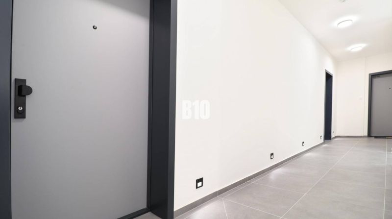 A hallway in a 2-room apartment with light-colored tiles and doors.