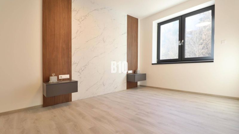 This room in a 2-room apartment has a floor with a wooden decor and a wall with a marble pattern.