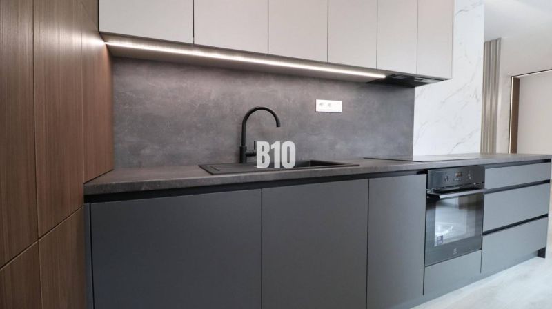 A kitchen unit in a 2-room apartment with a black sink and a built-in oven.
