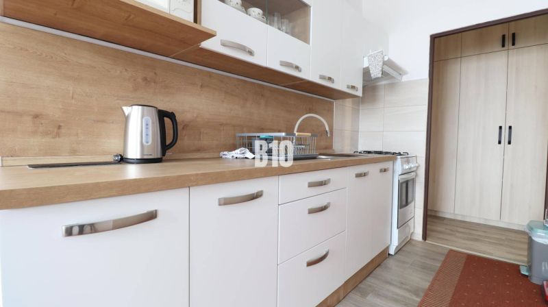 A bright kitchen with white cabinets and a wooden decor countertop in a 3-room apartment.