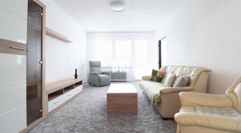 Living room in a 3-room apartment with a comfortable sofa and leather armchairs.