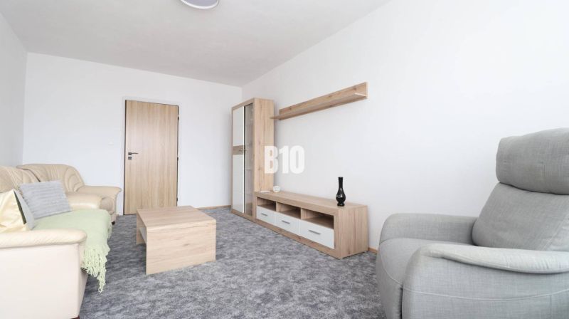 Living room with a beige sofa, gray armchair, and furniture with a wooden decor in a 3-room apartment.