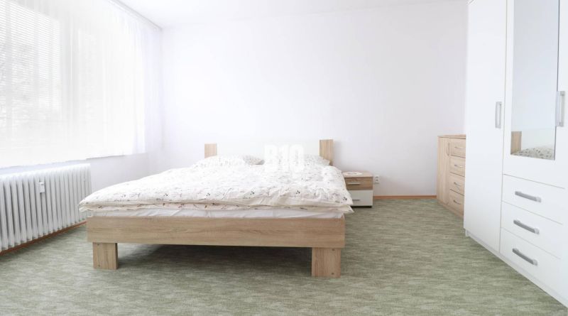 A bedroom in a 3-room apartment with a double bed, white furniture, and a carpet.