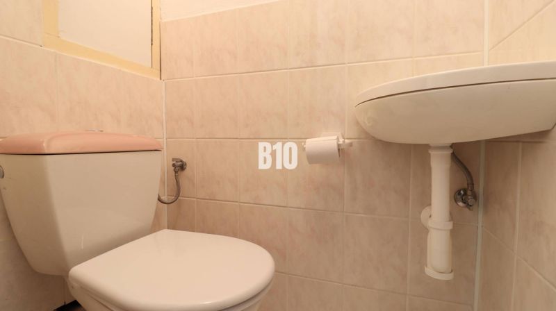 Toilet and sink in the bathroom of a 3-room apartment with tiles.