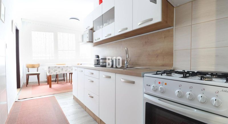 A kitchen in a 3-room apartment with a gas stove and a floor with a wood decor.