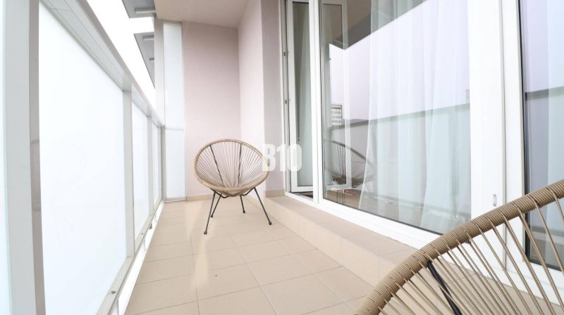 Balcony of a 1-room apartment with two chairs and sliding doors.