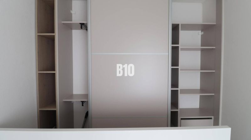 A built-in wardrobe in a studio apartment with open shelves and hanging space.