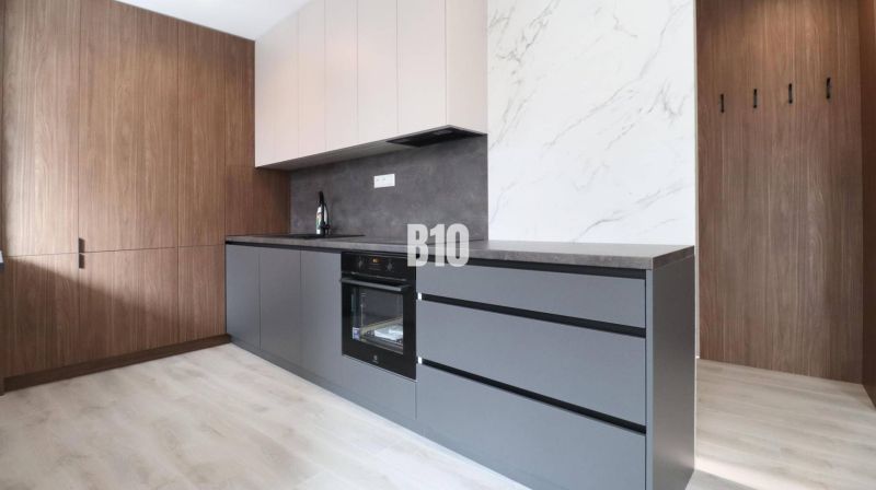 A kitchen in a 2-room apartment with a wooden decor floor and modern cabinets.