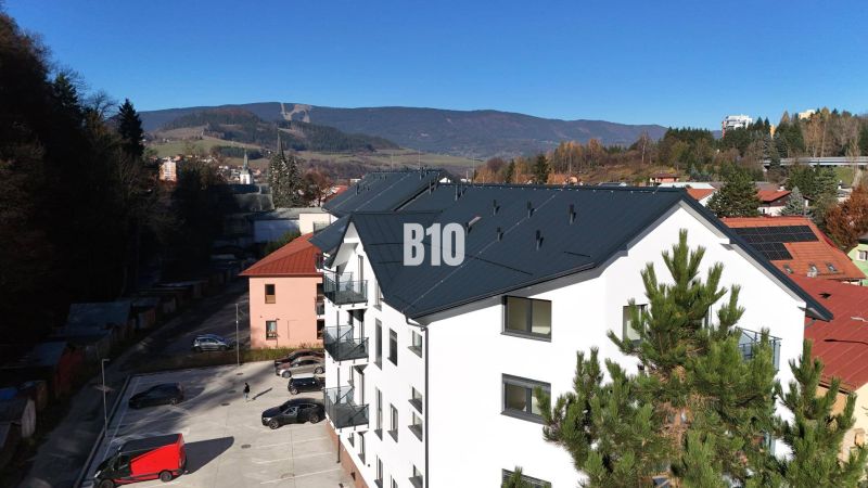 A new apartment building in Dolný Kubín, with a view of the mountains and a parking lot.