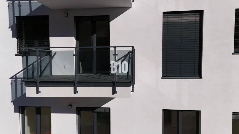 A balcony with glass railings and shutters on a two-room apartment building in Dolný Kubín.